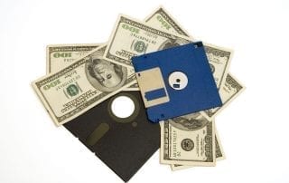 multiple hundred dollar bills underneath 5 ¼" floppy disk and 3 ½" computer disk